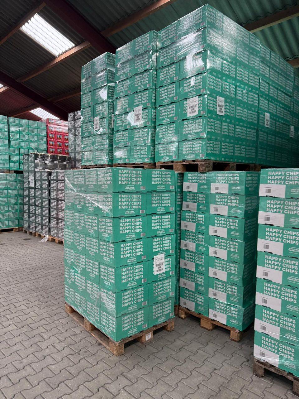 Gestapelde dozen chips sour cream, onion en chili op pallets