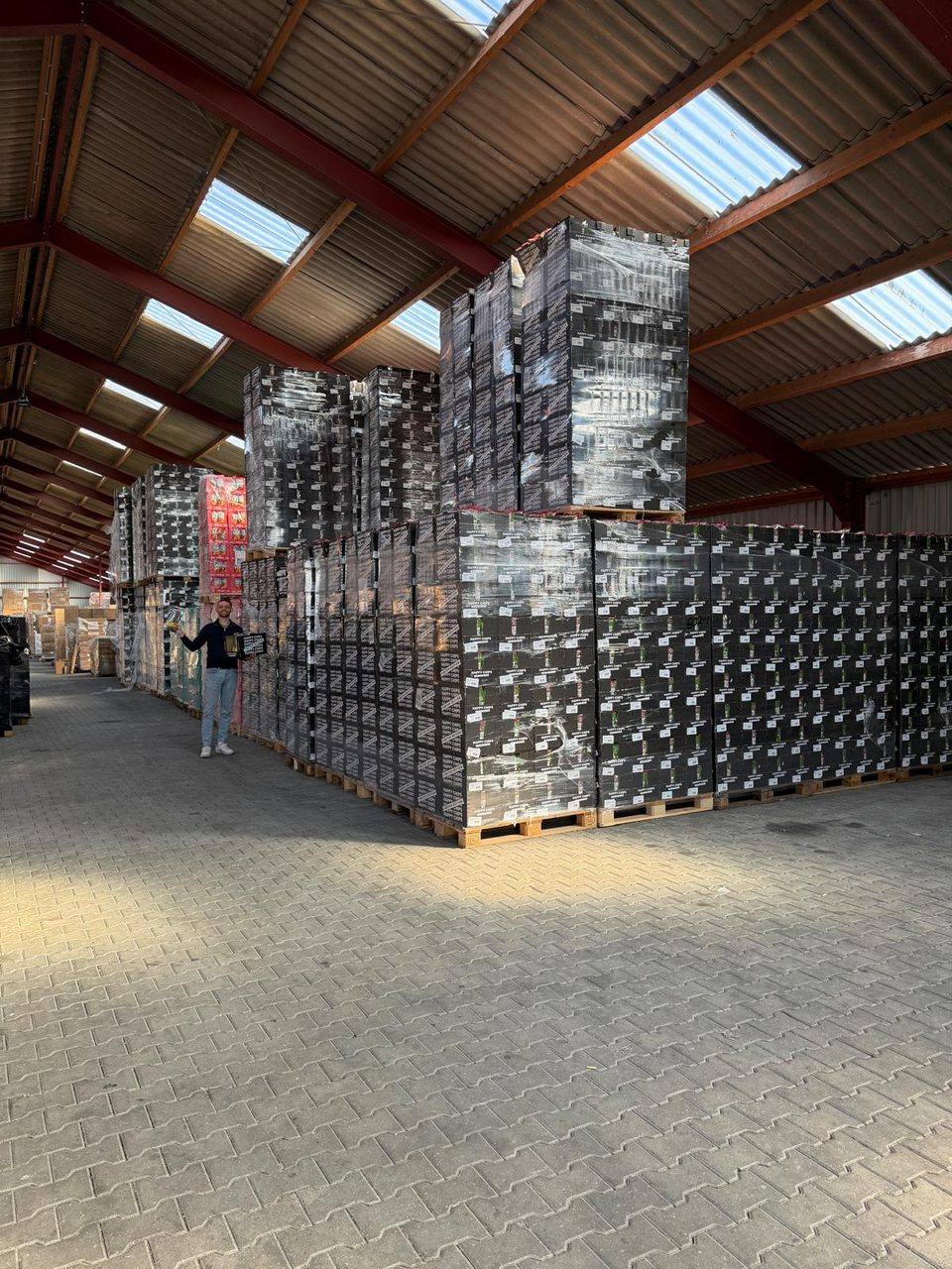 Rijen pallets chips in het magazijn, een medewerker ernaast geeft de schaal aan